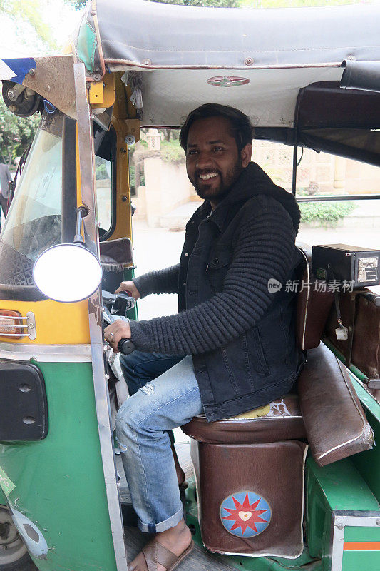 印度人驾驶机动三轮车/绿色和黄色嘟嘟车出租车司机在印度北部新德里的照片